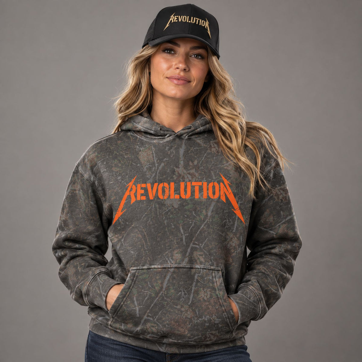 Shocker Logo Camo Heavyweight Hoodie worn by female model in studio, with Cowboy Revolution Gold Standard Shocker performance hat