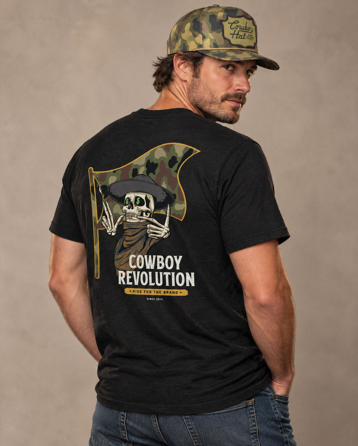 Male model in Cowboy Code #7 Ride for the Brand tee, Solid Black and Woodland Camo rope hat, Cowboy Revolution