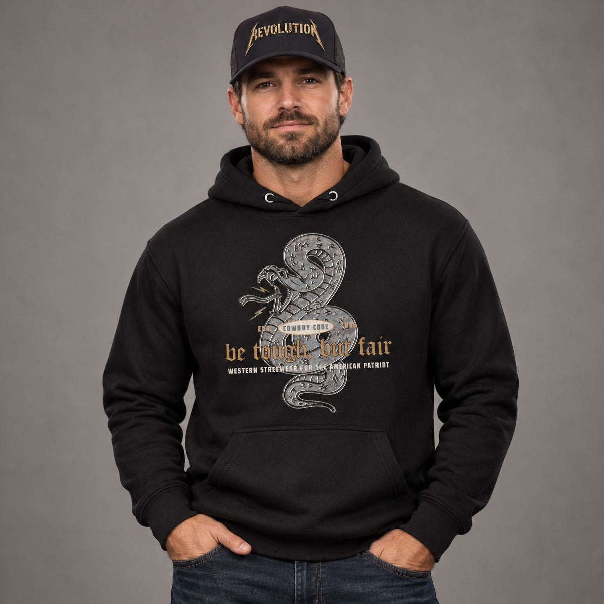 Cowboy Code #5 Tough But Fair hoodie worn by male model in studio, with Cowboy Revolution Gold Standard Shocker performance hat