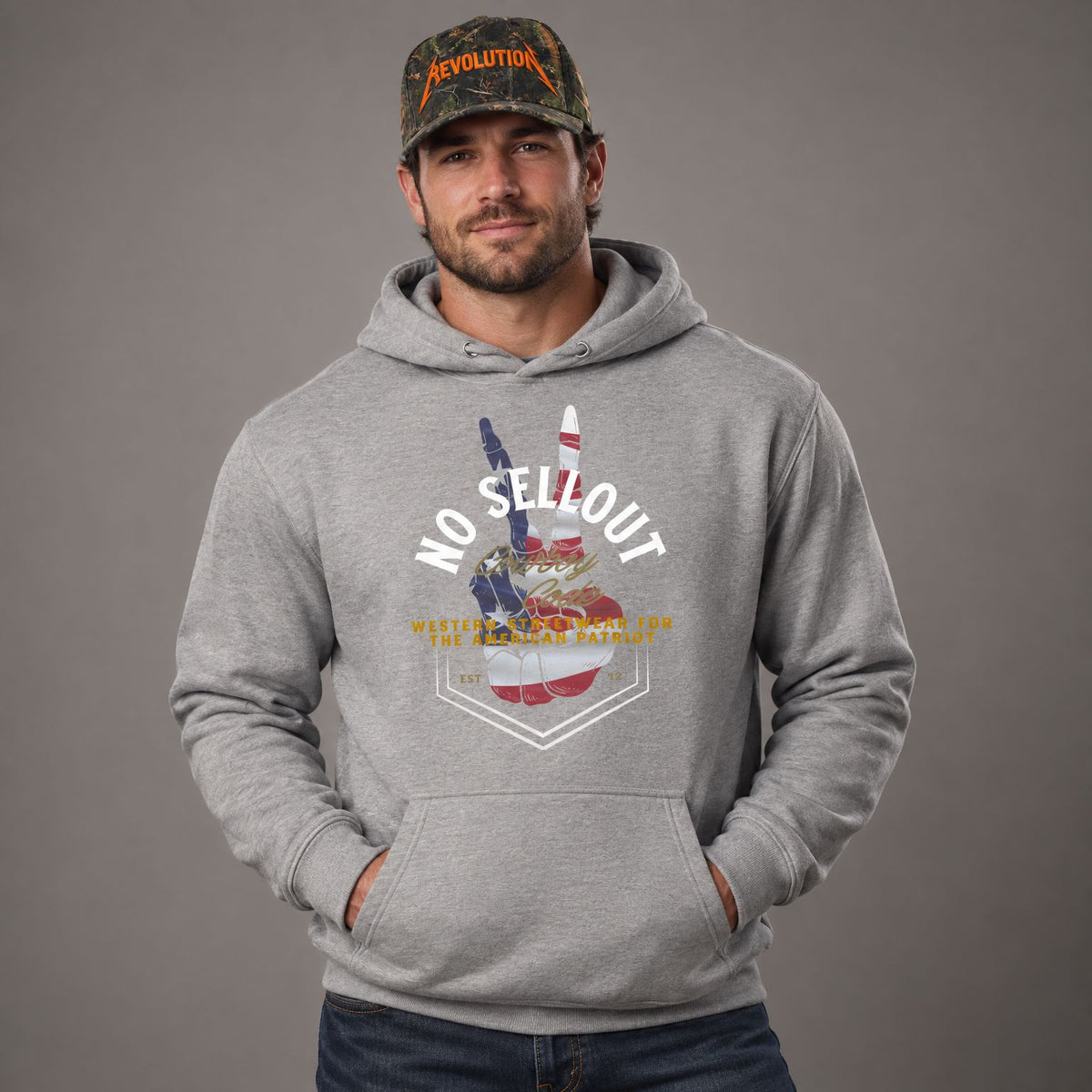 Cowboy Code #9 No Sellout hoodie worn by male model in studio, with Cowboy Revolution Backwoods Camo Shocker performance hat